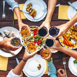 Big family dinner. Vertical top view on served table and hands with clinking goblets